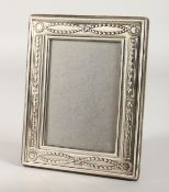 AN UPRIGHT PHOTOGRAPH FRAME with laurel wreath and garlands. 6.75ins x 5.5ins.