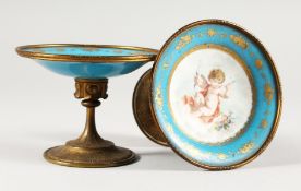 A GOOD SMALL PAIR OF SEVRES BLUE PORCELAIN TAZZAS with ormolu mounts painted with cupids. 4ins