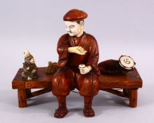 A JAPANESE MEIJI PERIOD CARVED IVORY AND WOOD OKIMONO OF A MONKEY TRAINER - seated upon a wooden