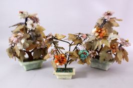 THREE CHINESE CARVED JADE MODEL TREES, each in carved pots with with carved flora, 28cm high &
