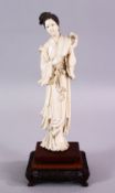 A 19TH CENTURY CHINESE CARVED IVORY FIGURE OF GUANYIN, stood holding a fan, on a carved wooden base,