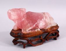 A CHINESE CARVED ROSE QUARTZ FIGURE OF A RECUMBENT OXEN, in a led position upon a carved hardwood