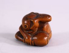 A JAPANESE MEIJI PERIOD CARVED BOXWOOD NETSUKE OF A MAN IN HIS LAP- the figure with his head down in