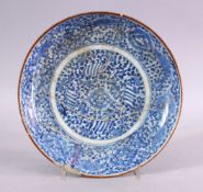 AN EARLY SAFAVID BLUE & WHITE PORCELAIN PLATE, decorated with scrolling floral design, (AF) 22CM.