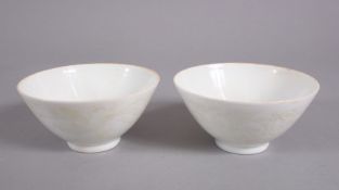 A PAIR OF CHINESE MING STYLE MONOCHROME CARVED PORCELAIN TEA BOWLS, with carved decorations of