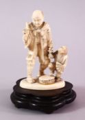 A JAPANESE MEIJI PERIOD CARVED IVORY OKIMONO GROUP - MONKEY TRAINER - the man stood with a monkey to