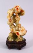 A CHINESE CARVED JADE FIGURE OF TWO LION DOGS, the dogs playing upon wooded outcrops, upon a