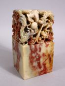 A LARGE CHINESE CARVED SOAPSTONE DRAGON SEAL, the top with openwork carving depicting intertwined