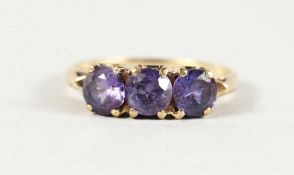 A 10K YELLOW GOLD THREE-STONE AMETHYST RING.