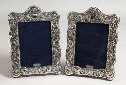 A PAIR OF SILVER REPOUSSE DESIGN PHOTOGRAPH FRAMES. 7.75ins x 5.5ins.