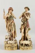 A PAIR OF ROYAL DUX PORCELAIN FIGURES depicting a shepherd playing pipes and a shepherdess. 15ins