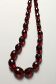 A LONG STRING OF CHERRY AMBER BEADS.