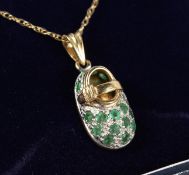 A 9CT GOLD, EMERALD AND DIAMOND BABIES BOOT PENDANT on a chain.