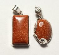TWO SILVER AND GOLD STONE PENDANTS.