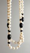 A LONG PEARL AND BLACK JET NECKLACE.