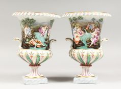A PAIR OF CAPODIMONTE TWO-HANDLED URNS, with nude figures bathing in relief, on square bases. N mark