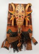 A NORTH AMERICAN INDIAN PAINTED LEATHER COVER, and a painted carved wood mask (2). Leather 30ins x