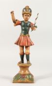 AN UNUSUAL CONTINENTAL POLYCHROME DECORATED POTTERY FIGURE modelled as a young soldier holding aloft
