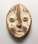 A SMALL CARVED WOOD AND PAINTED TRIBAL MASK. 7.5ins high.