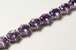 A SILVER OVAL CUT FIFTEEN STONE AMETHYST LINE BRACELET.