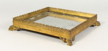 AN ORNATE ORMOLU AND MIRRORED PLATEAU, with pierced sides and dolphin feet. 12ins wide.