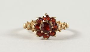 A 9CT YELLOW GOLD AND REDSTONE FLOWER RING.