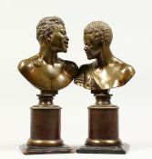 A GOOD PAIR OF SMALL BRONZE BUSTS of an African man and woman, on circular bronze bases. 11ins and