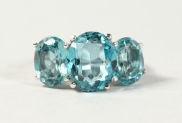 A SILVER THREE STONE OVAL CUT TOPAZ RING.