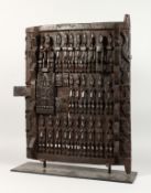 A DOGAN WOODEN SMALL DOOR carved all over with stylized figures and animals, on a later stand. 25ins