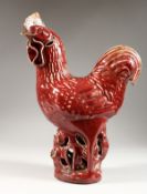A RED GLAZED POTTERY MODEL OF A CHICKEN. 14ins high.