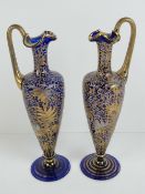 A pair of gilded and enamelled slender ewers in glass, each standing 24cm high.