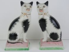 A pair of 20th century opposing seated Staffordshire style cats on cushions, each 18cm high.