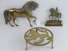 A brass lion ardent trivet together with a small brass door porter in the form of a mounted soldier,