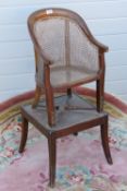A 19th century bergere metamorphic childs chair, raised over square shaped base,