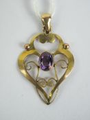 A 9ct gold Edwardian pendant having central oval cut amethyst, floral scroll work frame stamped 9ct,