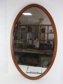 An oval Edwardian mahogany framed mirror cross-banded with walnut measuring 92 x 59cm.