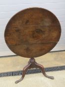 A 19th century circular oak tilt-top table raised over gun barrel stem upon three outswept legs,