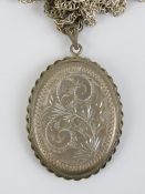 A HM silver locket, having engraved floral design to front and back, on sterling silver chain.