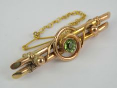 A rose metal double bar brooch having scrollwork upon and central round cut peridot approx 0.