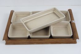 A Clarice Cliff hors d' oeuvres comprising a wooden tray having six square shaped 10cm dishes,