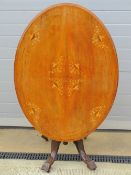 A late Victorian oval tilt top table having inlaid boxwood decoration, quarter veneered,