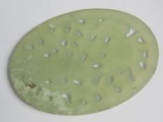 A pierced oval green jade Oriental disc,