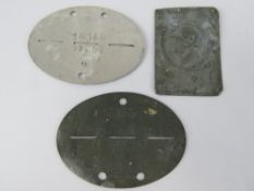 Two German dog tags together with a pressed metal plaque of a German soldier. Three items.
