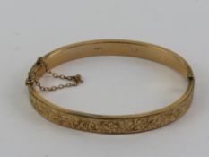 A vintage 9ct gold hinged bangle having floral engraving to front, Chester hallmark,