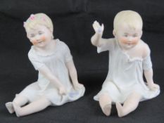 A pair of late 19th century Continental bisque seated child figurines, each approx 15cm high.