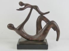 A bronzed brass sculpture of child and parent playing, 32cm wide.