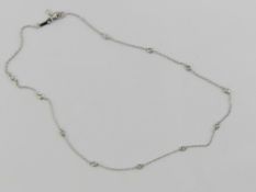 A 14ct white gold necklace having eleven round cut diamonds upon, stamped 585, adjustable length,