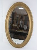 A gilt framed bevelled edge oval wall mirror, 80 x 52cm.