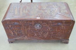 An early 20th century Oriental part carved camphor wood lidded trunk,