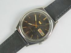 A Seiko 5 automatic wristwatch with black dial, yellow metal hands and batons,